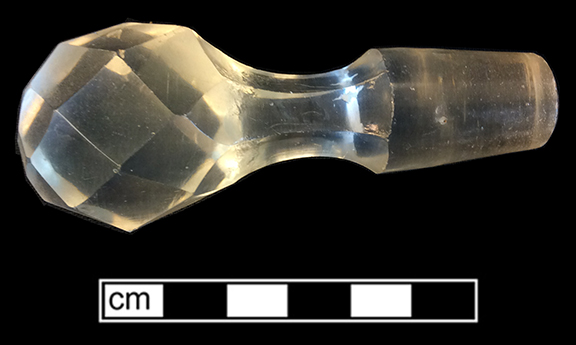 Colorless leaded glass stopper with six-sided stem. Length:  3.25”. 18BC33